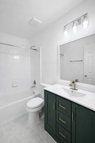 a bathroom with a granite countertop toilet a sink a mirror a bathtub and shower