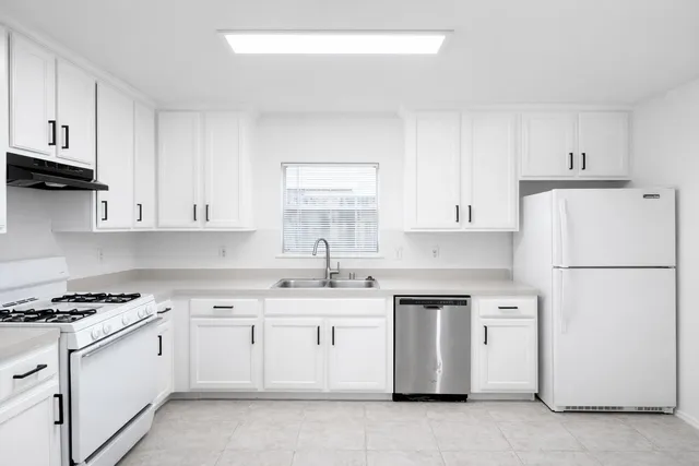 a kitchen with cabinets appliances a sink and a window