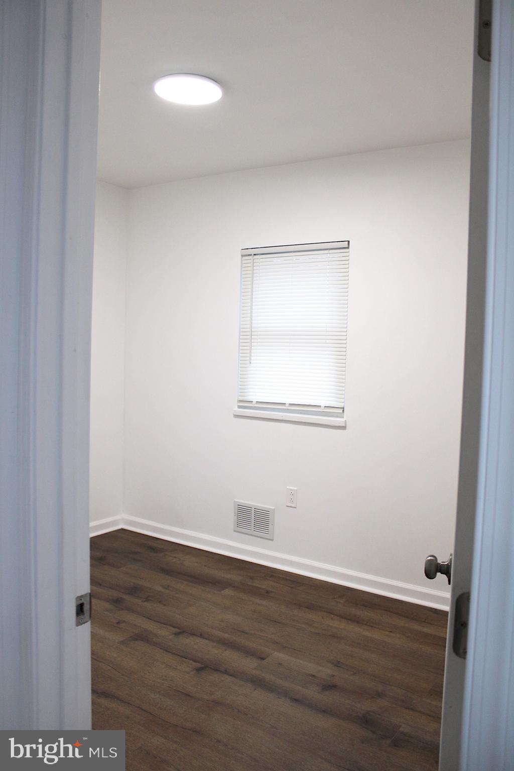 1128 West Browning Road, Unit 1 Bellmawr, NJ 08031 - Photo 14 of 19 a view of an empty room with wooden floor and a window