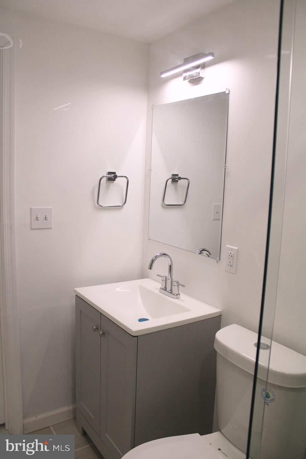 1128 West Browning Road, Unit 1 Bellmawr, NJ 08031 - Photo 17 of 19 a bathroom with a sink a toilet and mirror