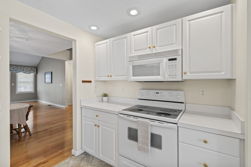 4 Strawberry Lane, Unit E Hudson, MA 01749 - Photo 8 of 40 a kitchen with white cabinets and white appliances