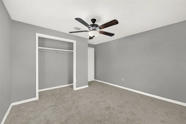 an empty room with closet and a ceiling fan