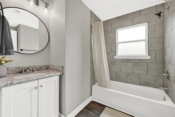 a bathroom with a granite countertop sink a mirror and a bathtub
