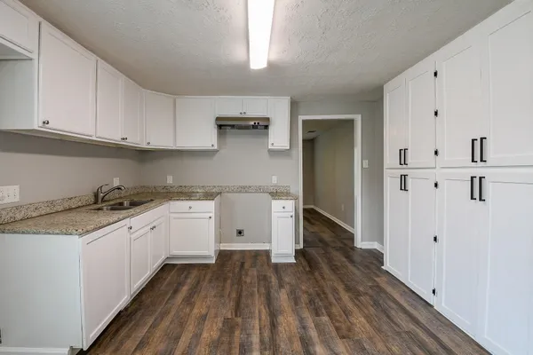a kitchen with granite countertop white cabinets and white appliances