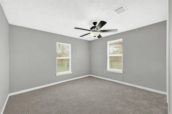 an empty room with windows and ceiling fan