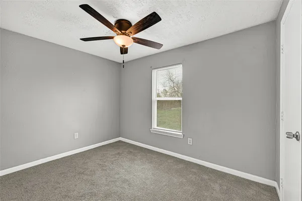 an empty room with a window and a fan