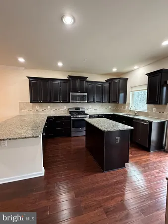 a kitchen with stainless steel appliances granite countertop a refrigerator a stove a sink and a oven