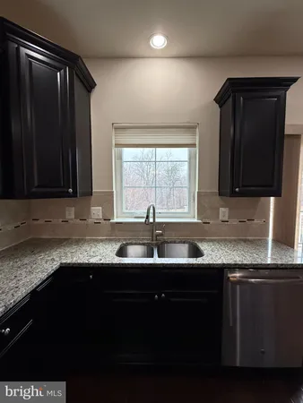 a large kitchen with granite countertop a large counter top stainless steel appliances and wooden floor
