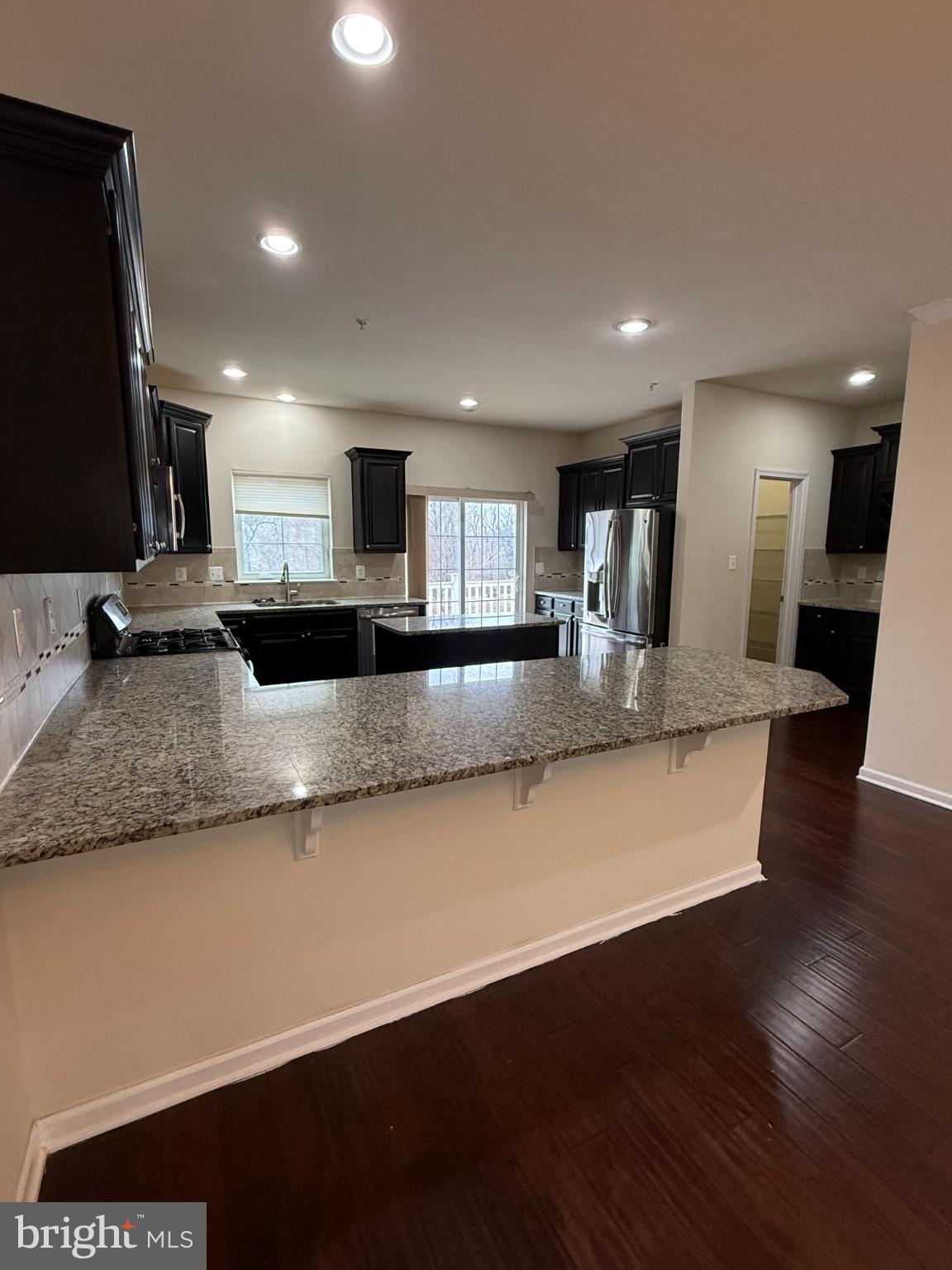 7018 Foxton Way Hanover, MD 21076 - Photo 23 of 72 a large kitchen with granite countertop a large counter top stainless steel appliances and wooden floor