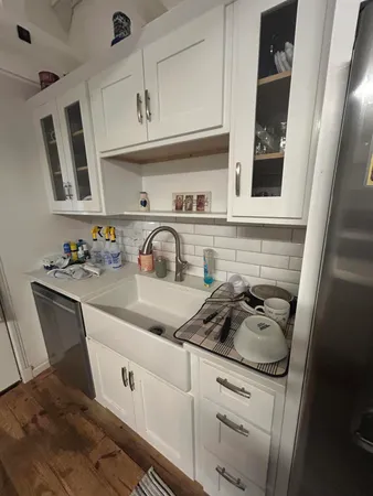 a kitchen with white cabinets and sink