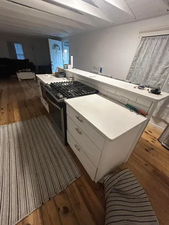 a kitchen with granite countertop a stove and a wooden floor