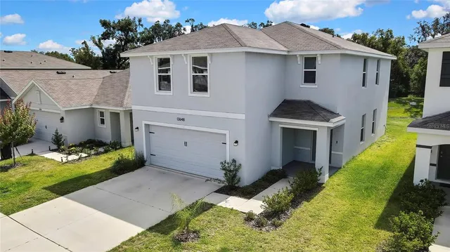 a view of a white house with a yard potted plants and a table and chair