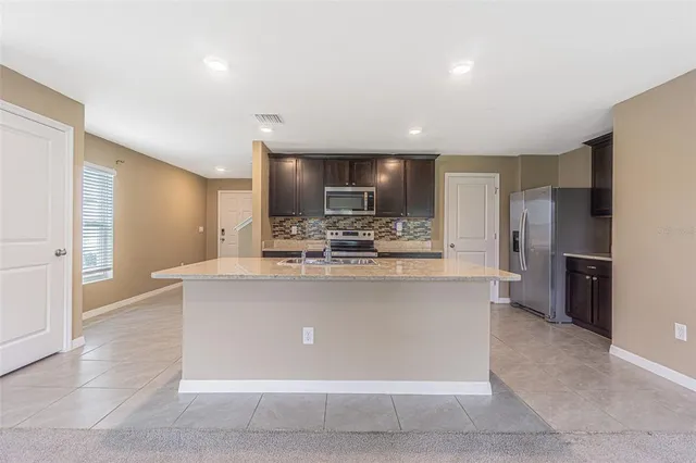 a kitchen with kitchen island stainless steel appliances a sink a stove a microwave a counter top and cabinets