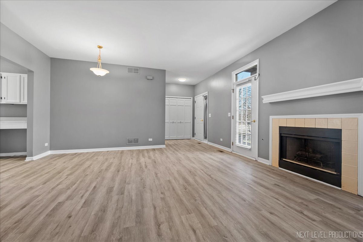 1247 Rhodes Lane Naperville, IL 60540 - Photo 3 of 19 an empty room with wooden floor fireplace and window