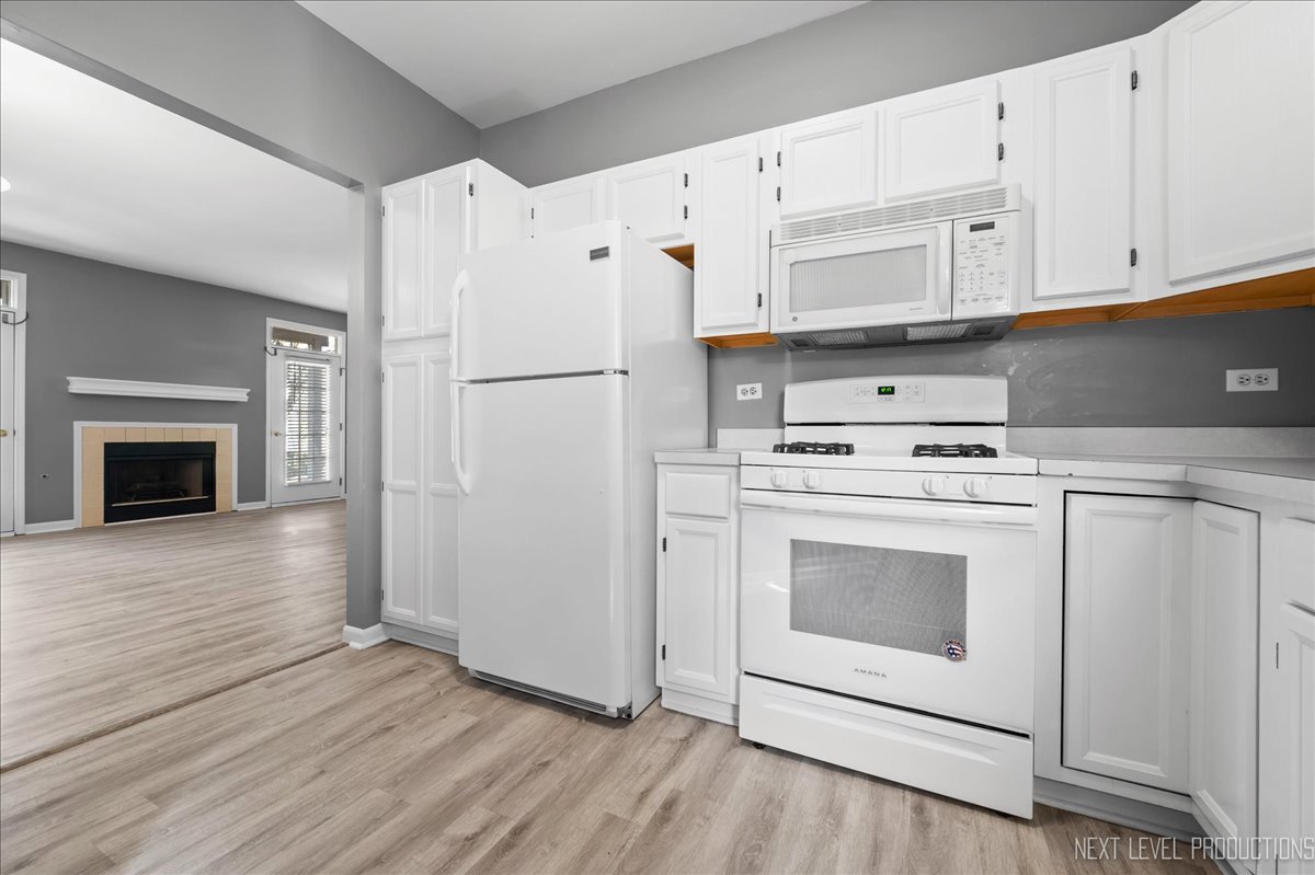 1247 Rhodes Lane Naperville, IL 60540 - Photo 8 of 19 a kitchen with white cabinets and white appliances