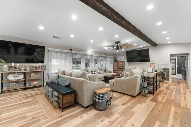 a large white kitchen with stainless steel appliances kitchen island a large counter top and a stove top oven