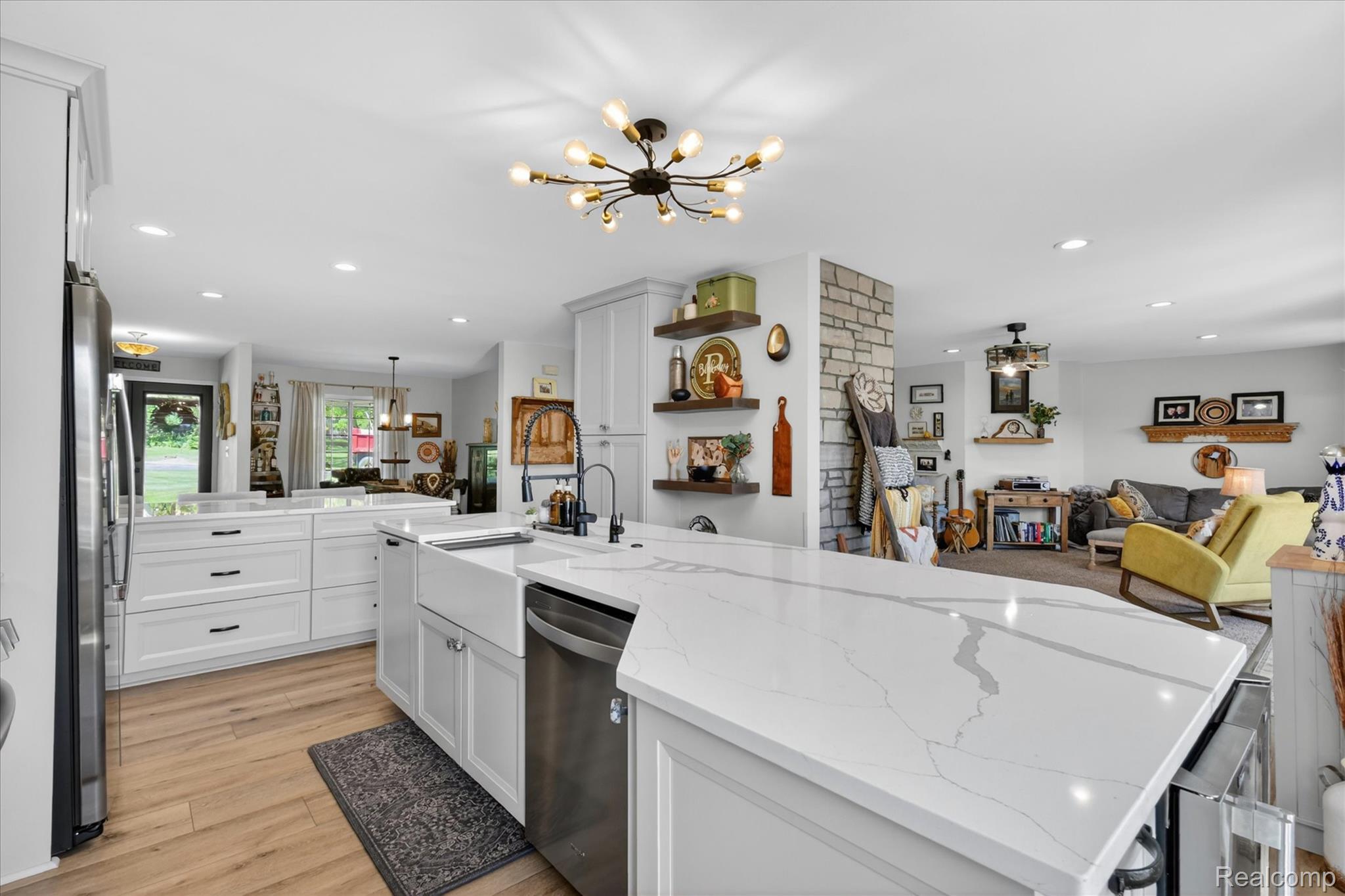 3860 East Commerce Road Commerce Township, MI 48382 - Photo 17 of 72 Kitchen featuring light wood-finish flooring, white cabinetry with black hardware, a stainless steel refrigerator, a white farmhouse sink, and white countertops with gray veining