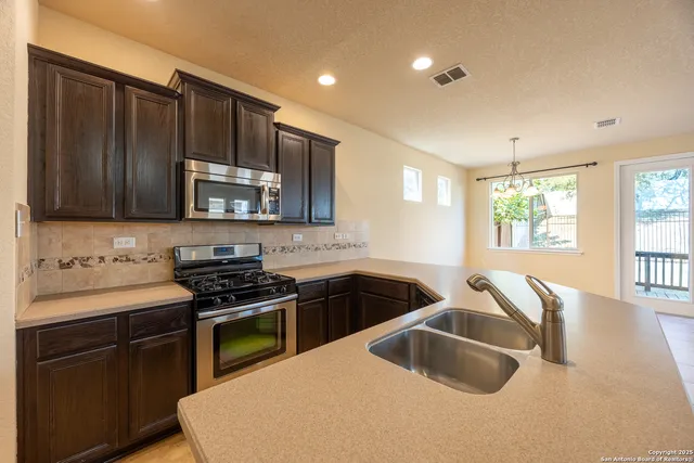 a kitchen that has a sink a stove and cabinets