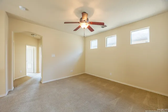 an empty room with windows and fan