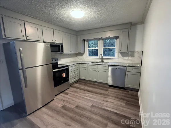 a kitchen with stainless steel appliances granite countertop a refrigerator a sink a stove a refrigerator and white cabinets