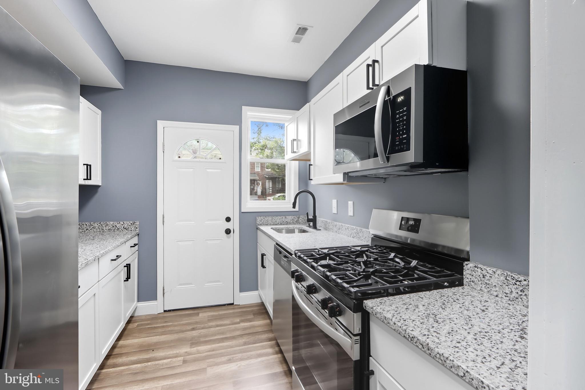 1309 East Patapsco Avenue Baltimore, MD 21225 - Photo 12 of 34 a kitchen with stainless steel appliances granite countertop a stove a microwave and a refrigerator