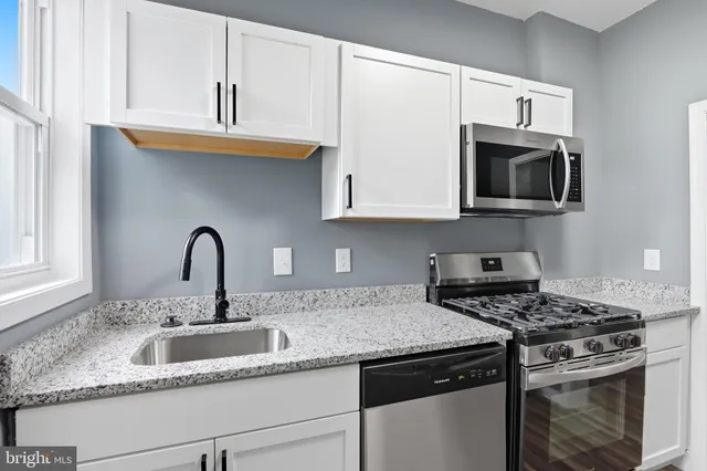 a kitchen with granite countertop a sink stainless steel appliances and cabinets