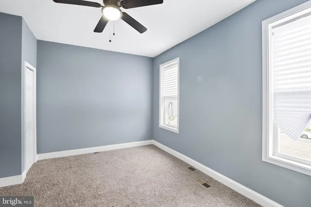 an empty room with windows and ceiling fan
