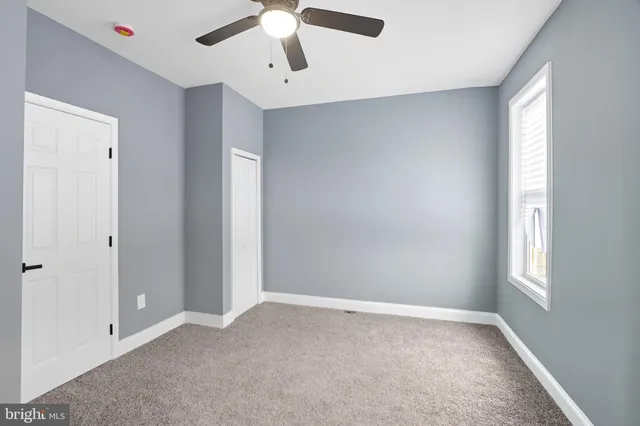 an empty room with windows and fan