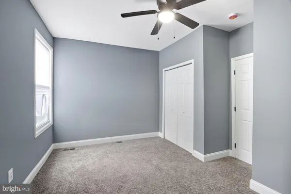 a view of an empty room with window and chandelier fan