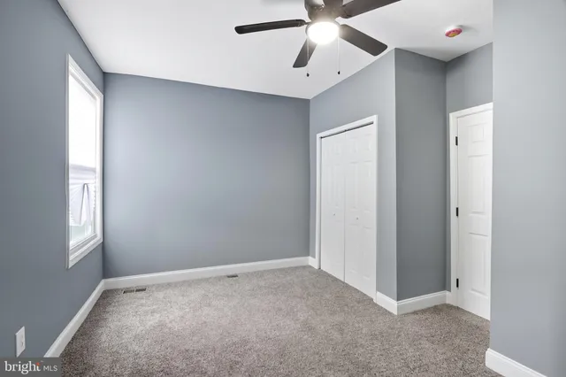 a view of an empty room with window and chandelier fan