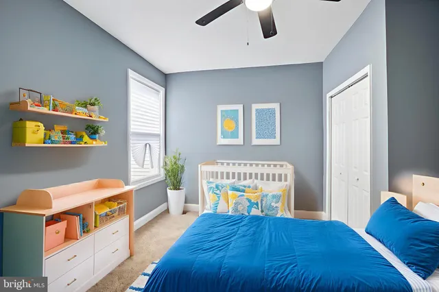 a bedroom with a bed and a lamp on dresser next to a window