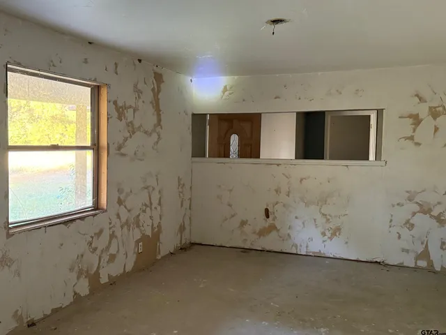 a view of a livingroom with an empty space & a window