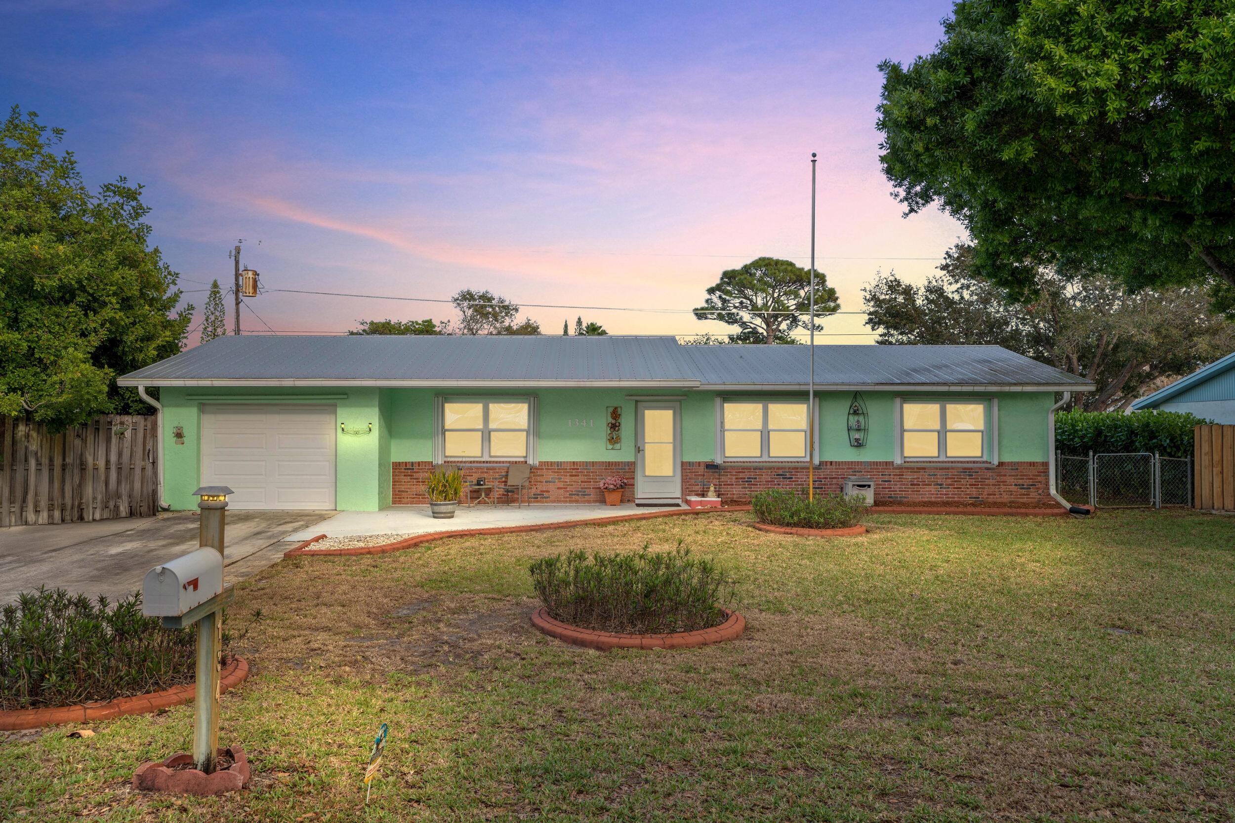 1341 Southeast Seashell Lane Stuart, FL 34996 - Photo 1 of 24 a front view of a house with a yard outdoor seating and covered with trees