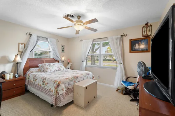a bedroom with a bed a flat screen tv and a window
