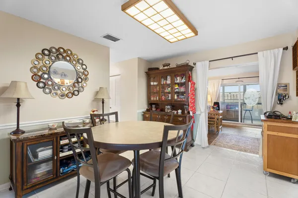 a view of a dining room and livingroom with furniture wooden floor a rug a painting and a chandelier