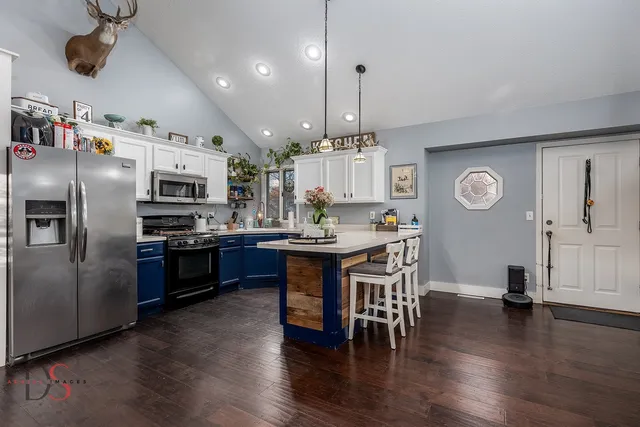 a kitchen with stainless steel appliances kitchen island granite countertop a table chairs and a refrigerator