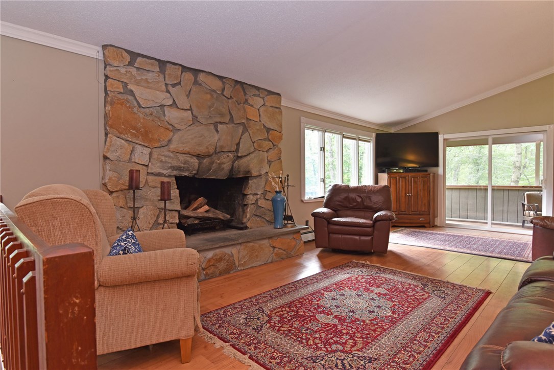 33 Ramble Road Glocester, RI 02857 - Photo 6 of 22 Living room with stone fireplace, with wide plank laminate flooring and view of screened porch in the distance.