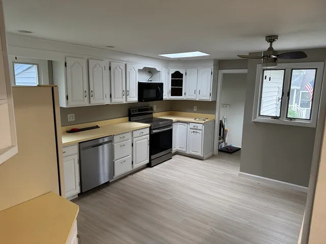 a kitchen with stainless steel appliances granite countertop a stove top oven a sink dishwasher and a refrigerator with wooden floor