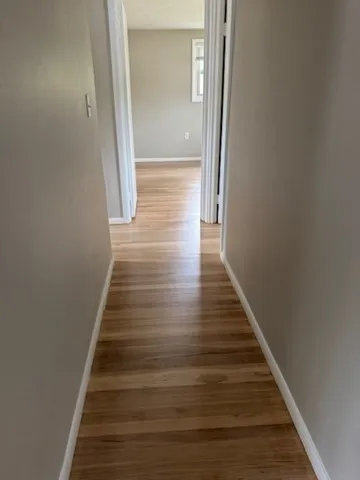 a view of a hallway with wooden floor and entryway