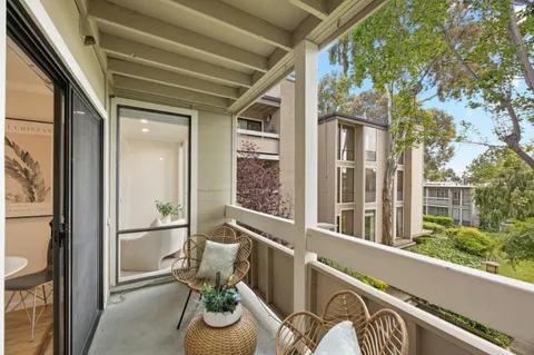 a view of a balcony with chairs and floor to ceiling window
