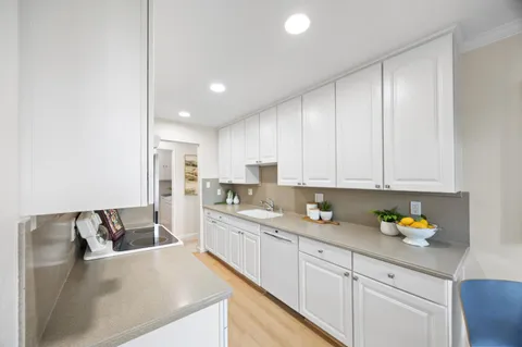 a kitchen with stainless steel appliances granite countertop a sink a stove and white cabinets