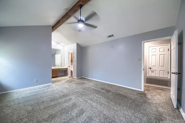 an empty room with chandelier fan and windows