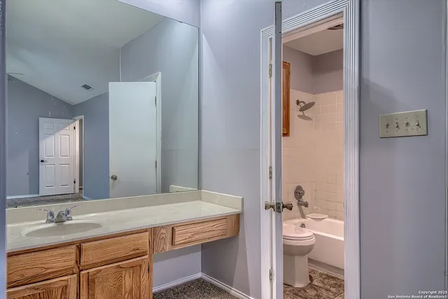 a bathroom with a granite countertop sink a toilet and a mirror