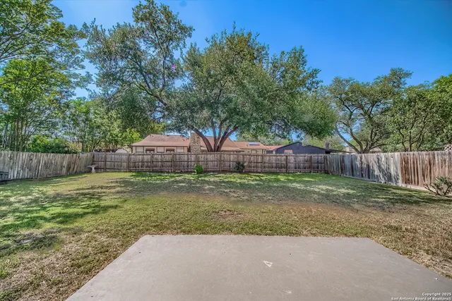 a backyard of a house with a trees and wooden fence