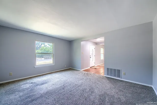 a view of an empty room with a window and closet area