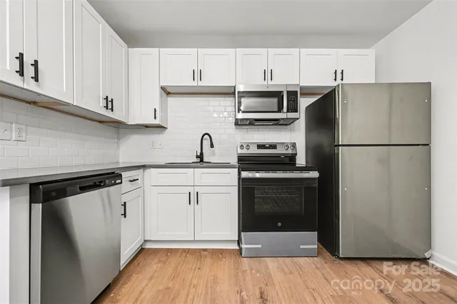 a kitchen with cabinets stainless steel appliances and wooden floor