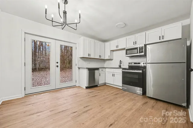 a kitchen with stainless steel appliances granite countertop a refrigerator a stove a sink and white cabinets