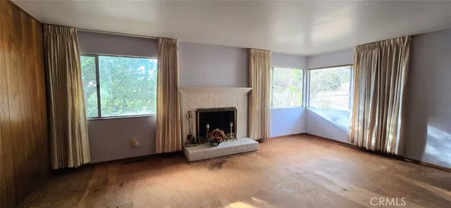 a view of an empty room with windows and a fireplace