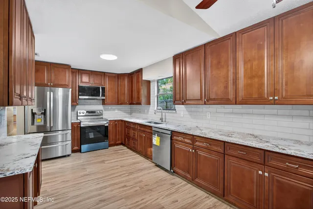 a kitchen with stainless steel appliances granite countertop wooden cabinets a stove top oven a sink and dishwasher