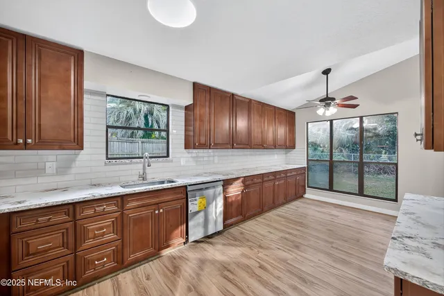 a kitchen with stainless steel appliances granite countertop wooden cabinets a sink dishwasher a stove and a refrigerator with wooden floor